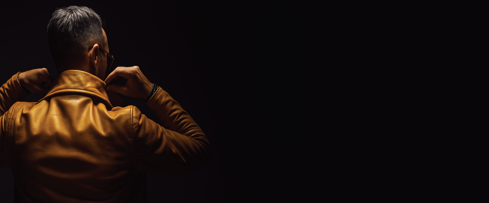 Person wearing a brown leather jacket in a dark setting